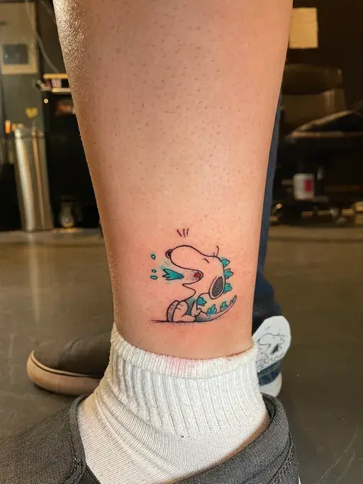 small cartoon beagle tattoo with dinosaur costume on ankle