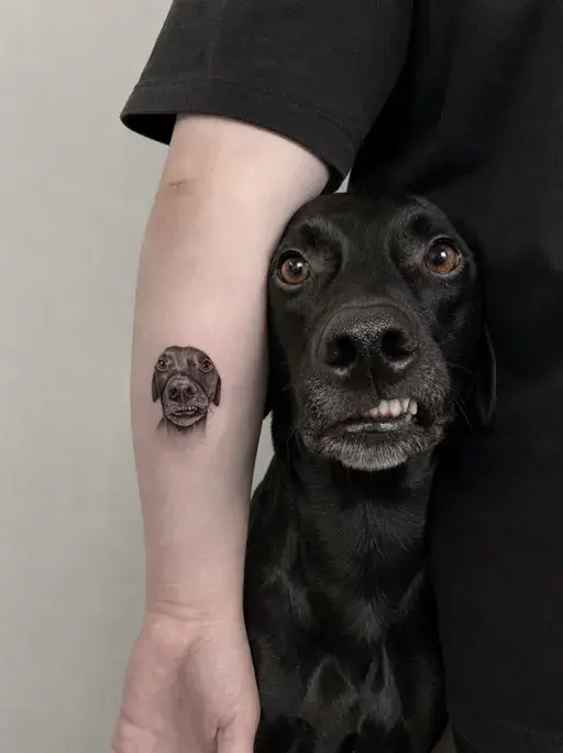 tiny realistic black lab portrait tattoo on inner forearm